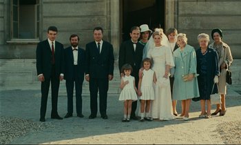 Movie still from “Happiness” (1965), directed by Agnès Varda – A group of men and women standing in front of a building; Wide shot, High angle