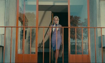 Movie still from “Happiness” (1965), directed by Agnès Varda – A woman in a blue dress is walking down the stairs; Wide shot, Low angle