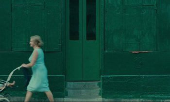 Movie still from “Happiness” (1965), directed by Agnès Varda – A woman in a blue dress is walking down the street; Wide shot, Over the shoulder angle