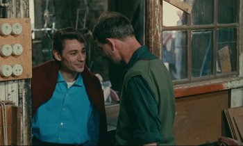 Movie still from “Happiness” (1965), directed by Agnès Varda – Two men talking to each other in front of a window; Medium shot, Over the shoulder angle