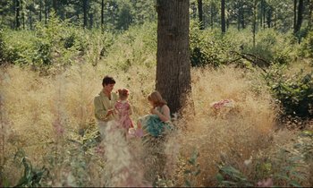 Movie still from “Happiness” (1965), directed by Agnès Varda – Two women and a child sitting in a field; Extreme Wide shot, High angle