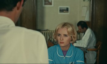 Movie still from “Happiness” (1965), directed by Agnès Varda – A woman wearing a blue and white nurse's uniform; Medium shot, Over the shoulder angle