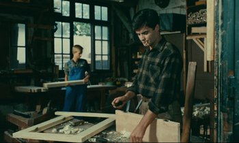 Movie still from “Happiness” (1965), directed by Agnès Varda – A man and a woman working in a wood shop; Medium shot, Low angle