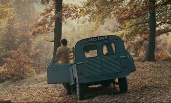 Movie still from “Happiness” (1965), directed by Agnès Varda – A man standing next to an old school bus; Extreme Wide shot, High angle