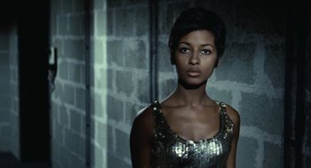 Movie still from “Le Samouraï” (1967), directed by Jean-Pierre Melville – A woman in a silver dress standing next to a brick wall; Close Up shot, Low angle