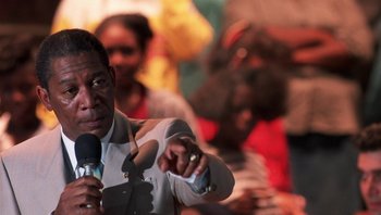 Movie still from “Lean on Me” (1989), directed by John G. Avildsen – A man holding a microphone and pointing at a crowd of onlookers; Close Up shot, Over the shoulder angle