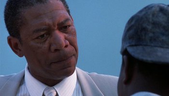 Movie still from “Lean on Me” (1989), directed by John G. Avildsen – An older black man wearing a suit and tie; Close Up shot, Over the shoulder angle