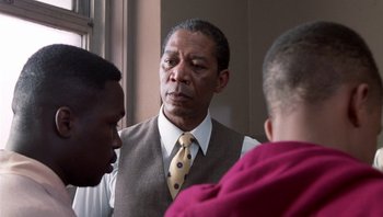 Movie still from “Lean on Me” (1989), directed by John G. Avildsen – A man in a vest and tie talking to two other men in front of a mirror; Close Up shot, Over the shoulder angle