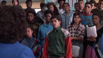 Movie still from “Lean on Me” (1989), directed by John G. Avildsen – A large group of young people standing in a room; Medium shot, High angle