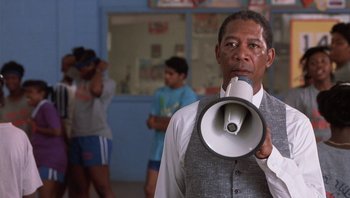 Movie still from “Lean on Me” (1989), directed by John G. Avildsen – A man holding a megaphone in front of a group of people; Medium shot, Low angle
