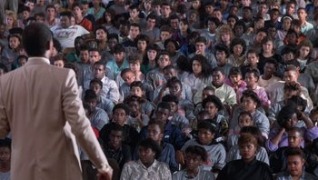 Movie still from “Lean on Me” (1989), directed by John G. Avildsen – A crowd of people sitting in a room; Wide shot, High angle