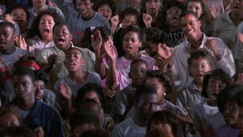 Movie still from “Lean on Me” (1989), directed by John G. Avildsen – A group of young people standing in front of a crowd; Medium shot, High angle