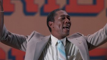 Movie still from “Lean on Me” (1989), directed by John G. Avildsen – A man in a gray suit and a blue striped tie; Close Up shot, Low angle