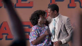 Movie still from “Lean on Me” (1989), directed by John G. Avildsen – An older man and a younger woman are embracing; Medium shot, Over the shoulder angle