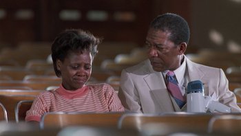 Movie still from “Lean on Me” (1989), directed by John G. Avildsen – A man and a woman sitting next to each other; Medium shot, Low angle