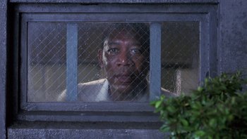 Movie still from “Lean on Me” (1989), directed by John G. Avildsen – A man looking out of a jail cell through a window; Close Up shot, Low angle
