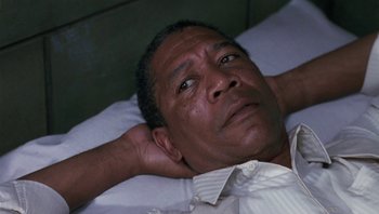 Movie still from “Lean on Me” (1989), directed by John G. Avildsen – A man laying in a bed with his hands behind his head; Close Up shot, High angle