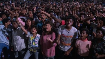 Movie still from “Lean on Me” (1989), directed by John G. Avildsen – A group of people standing in front of an audience; Wide shot, High angle