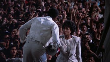 Movie still from “Lean on Me” (1989), directed by John G. Avildsen – A couple of people that are in front of a crowd; Medium shot, High angle