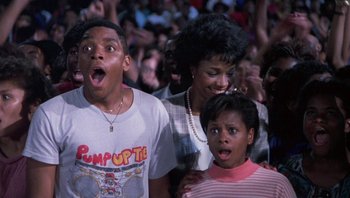 Movie still from “Lean on Me” (1989), directed by John G. Avildsen – A group of people standing in front of an audience; Close Up shot, High angle