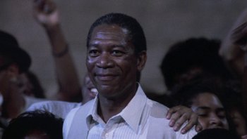Movie still from “Lean on Me” (1989), directed by John G. Avildsen – An older black man with his arms around a younger black man; Close Up shot, Low angle