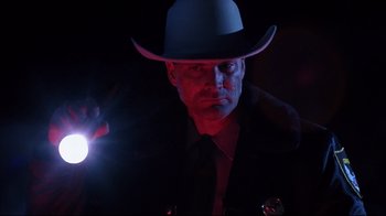 Movie still from “Leatherface: Texas Chainsaw Massacre III” (1990), directed by Jeff Burr – A man wearing a cowboy hat and holding a flashlight in the dark; Close Up shot, Low angle