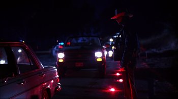 Movie still from “Leatherface: Texas Chainsaw Massacre III” (1990), directed by Jeff Burr – A police officer standing on the side of the road at night; Medium shot, Low angle