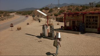 Movie still from “Leatherface: Texas Chainsaw Massacre III” (1990), directed by Jeff Burr – A man walking down a dirt road next to gas pumps; Extreme Wide shot, High angle