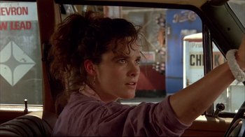 Movie still from “Leatherface: Texas Chainsaw Massacre III” (1990), directed by Jeff Burr – A young woman driving a car in the street; Close Up shot, Low angle