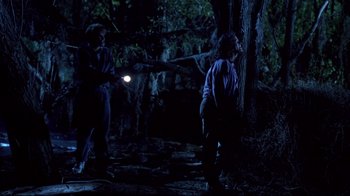 Movie still from “Leatherface: Texas Chainsaw Massacre III” (1990), directed by Jeff Burr – A couple of people in the woods at night with a flashlight; Wide shot, Low angle