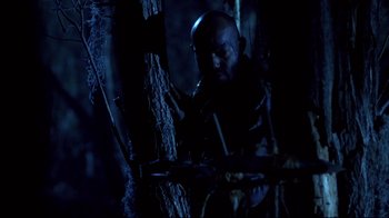 Movie still from “Leatherface: Texas Chainsaw Massacre III” (1990), directed by Jeff Burr – A man standing next to a tree in the dark; Medium shot, Low angle