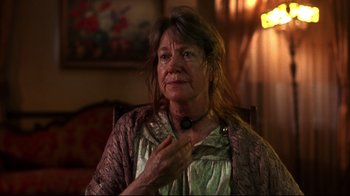 Movie still from “Leatherface: Texas Chainsaw Massacre III” (1990), directed by Jeff Burr – An older woman sitting in a chair with her hand up to her chest; Close Up shot, Low angle