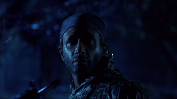 Movie still from “Leatherface: Texas Chainsaw Massacre III” (1990), directed by Jeff Burr – A man with a bandanna on his head is standing in the dark; Close Up shot, Low angle
