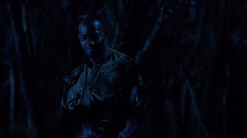 Movie still from “Leatherface: Texas Chainsaw Massacre III” (1990), directed by Jeff Burr – A man standing in the dark in a forest; Medium shot, Low angle