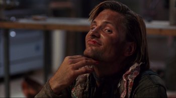 Movie still from “Leatherface: Texas Chainsaw Massacre III” (1990), directed by Jeff Burr – A person sitting down with his hand on his chin; Close Up shot, Low angle