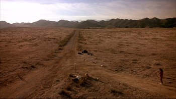 Movie still from “Leatherface: Texas Chainsaw Massacre III” (1990), directed by Jeff Burr – An empty dirt road in the middle of a desert; Extreme Wide shot, High angle
