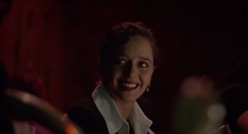 Movie still from “Leaving Las Vegas” (1995), directed by Mike Figgis – A woman smiling for the camera in a dark room; Close Up shot, Low angle