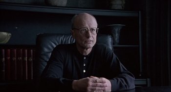 Movie still from “Leaving Las Vegas” (1995), directed by Mike Figgis – An older man sitting in a chair with his arms crossed; Close Up shot, Low angle