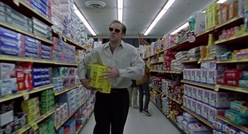 Movie still from “Leaving Las Vegas” (1995), directed by Mike Figgis – A man walking down a aisle in a store holding a box; Medium shot, Low angle