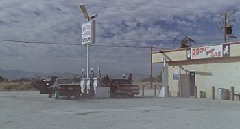 Movie still from “Leaving Las Vegas” (1995), directed by Mike Figgis – A gas station with cars parked on the side of the road; Extreme Wide shot, Low angle