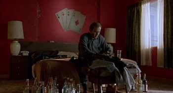 Movie still from “Leaving Las Vegas” (1995), directed by Mike Figgis – A man sitting on a chair next to a bed; Medium shot, Low angle