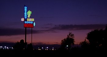 Movie still from “Leaving Las Vegas” (1995), directed by Mike Figgis – A motel sign lit up at night with a sky background; Extreme Wide shot, Low angle