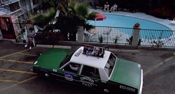 Movie still from “Leaving Las Vegas” (1995), directed by Mike Figgis – A green taxi cab with a picture on the top of it; Wide shot, Overhead angle