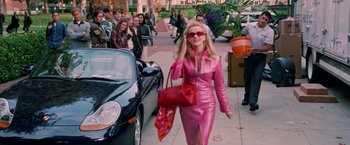 Movie still from “Legally Blonde” (2001), directed by Robert Luketic – A woman walking down a street holding a red purse; Wide shot, High angle