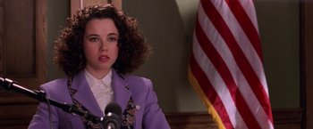 Movie still from “Legally Blonde” (2001), directed by Robert Luketic – A woman in a purple jacket is sitting in front of a microphone; Close Up shot, Over the shoulder angle