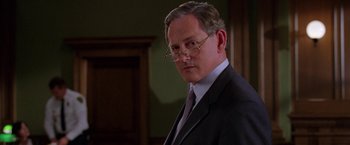 Movie still from “Legally Blonde” (2001), directed by Robert Luketic – A man in a suit and tie wearing glasses; Close Up shot, Over the shoulder angle