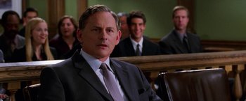 Movie still from “Legally Blonde” (2001), directed by Robert Luketic – A man in a suit sitting in front of other people; Close Up shot, Over the shoulder angle