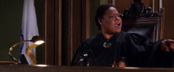 Movie still from “Legally Blonde” (2001), directed by Robert Luketic – A woman in a black robe is speaking at a podium; Medium shot, Low angle