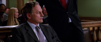 Movie still from “Legally Blonde” (2001), directed by Robert Luketic – A man in a suit and tie sitting in a room; Close Up shot, Over the shoulder angle