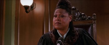 Movie still from “Legally Blonde” (2001), directed by Robert Luketic – A woman wearing a wig and a gown in front of a microphone; Close Up shot, High angle